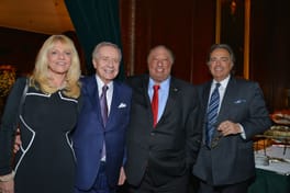 Margo and John Catsimatidis with two guests in a paneled room