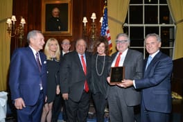 A plaque presentation, John and Margo Catsimatidis in a group of seven