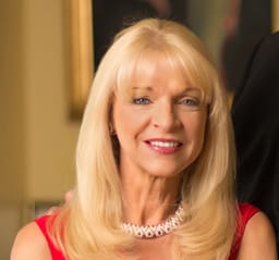 Margo Catsimatidis, smiling, in red, with a pearl necklace